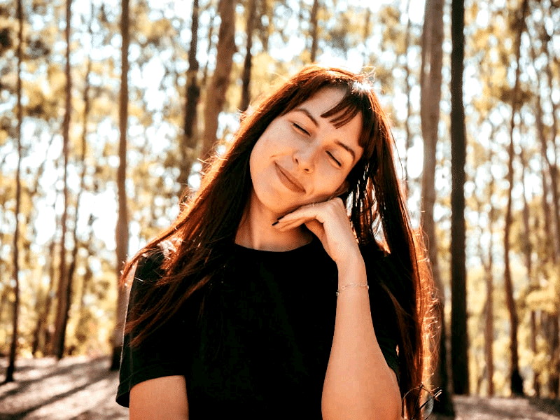 Calm woman standing in woodland.
